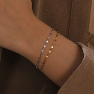 Minimalist 18K gold and silver thin chain bracelets set shown on a model's wrist