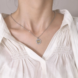 Detail of silver Love sun and moon couple necklace worn on a white shirt