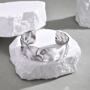 Close-up of silver irregular wide open bangle with textured hammered finish on stone