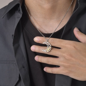 Detail of crescent moon pendant with Love lettering on silver chain worn by a model