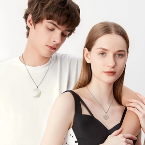 Detail of couple necklaces with moon and sun pendants featuring Love engraving and zircons