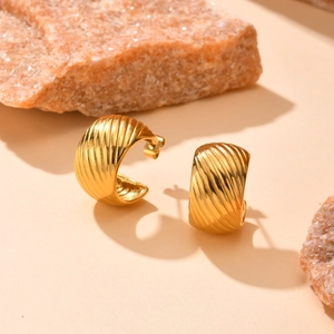 Détail des boucles d'oreilles créoles dorées en acier inoxydable avec motif torsadé