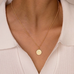 Collier doré en acier inoxydable avec pendentif corail rond porté par un mannequin
