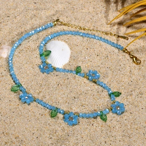 Détail de perles marguerites bleues et feuilles vertes sur un collier d'été de plage