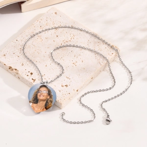 Close-up of heart-shaped silver photo locket necklace on a natural stone background