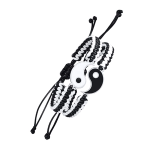 Detail of woven Yin Yang bracelets with magnetic heart charm for couples in black and white