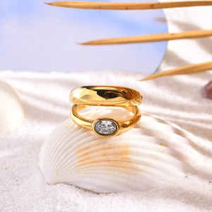 Detail of gold oval zircon rings set on a white shell and sand background