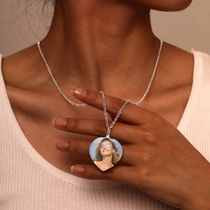 Custom heart-shaped photo locket necklace in silver worn by a model in warm lighting