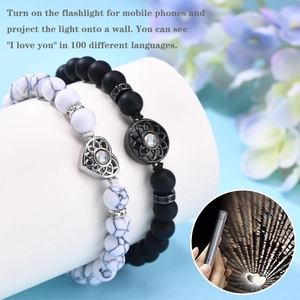 Détail de bracelets perlés pour couple avec breloque cœur et fonction de projection