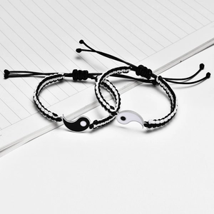 Detail of adjustable Yin Yang braided couple bracelets with heart magnets on notebook