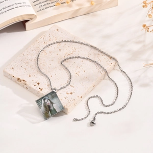 Close-up of square silver pendant necklace with personalized color photo on stone texture
