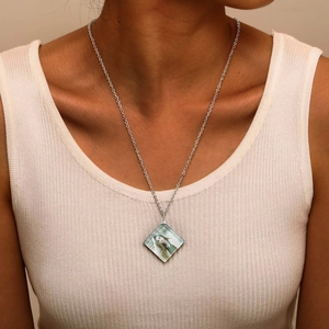Close-up of personalized square geometric crystal photo pendant necklace on white top