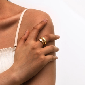 Minimalist gold double-band ring with oval zircon on hand of a model with white background