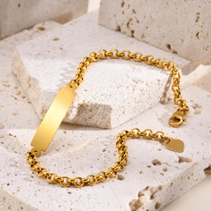 Macro detail of gold stainless steel ID plate bracelet with round links and heart charm