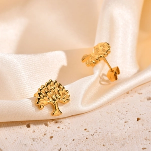 Macro view of gold Tree of Life stud earrings on soft silk and stone texture