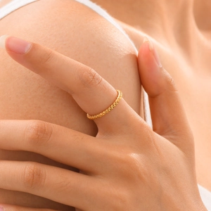 Detailed view of a gold thin geometric ring with texture worn on a finger