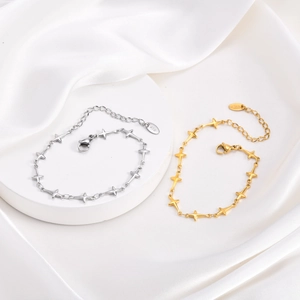 Bracelets étoiles à quatre branches en acier doré et argenté sur socle en soie