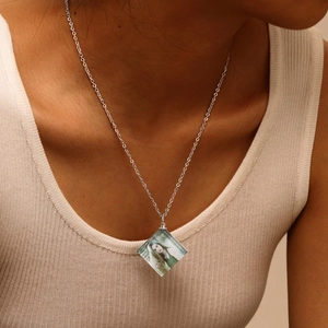 Close-up of a silver necklace featuring a custom diamond-shaped photo pendant