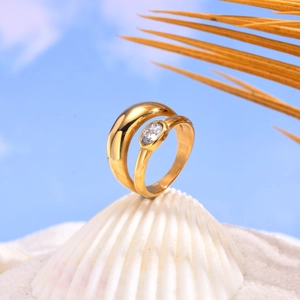 Elegant gold double band ring with oval zircon on white shell with beach background