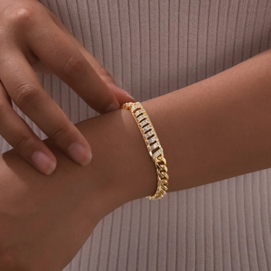 Close-up of golden Cuban link bracelet with sparkling zircon pave setting on a model