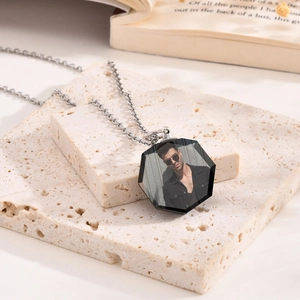 Custom hexagonal photo pendant necklace with silver chain displayed on stone props