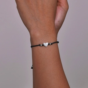 Minimalist black woven rope bracelet with heart pendant on wrist for mother and daughter