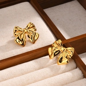 Élégantes boucles d'oreilles nœud en acier doré dans un écrin à bijoux en bois