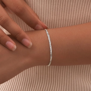 Detail of elegant silver braided stainless steel rope chain bracelet worn on a female wrist