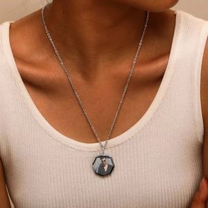 Close-up of a silver necklace featuring a custom hexagonal photo pendant on a model