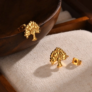 Golden Tree of Life stainless steel stud earrings with polished finish on a wooden bowl