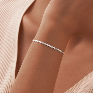 Close-up of a silver stainless steel braided rope chain bracelet on a woman's wrist