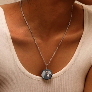 Close-up of hexagonal crystal photo pendant necklace worn by model on white knit top