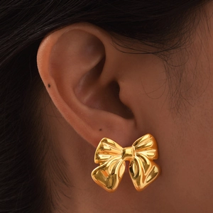 Boucles d'oreilles nœud en acier inoxydable doré portées pour un aperçu de la taille réelle
