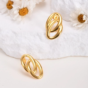 Elegant gold-tone double oval interlocking stud earrings on a minimalist decorative stone