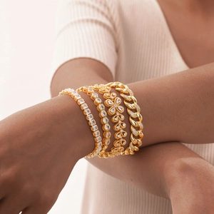 Set of four gold-plated bracelets featuring cubic zirconia and clover motifs on wrist