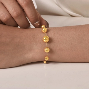 Collier à billes en acier inoxydable doré minimaliste porté par un mannequin élégant
