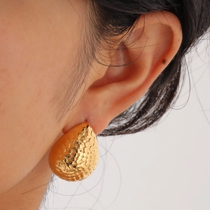 Boucles d'oreilles goutte dorées avec texture martelée portées par un mannequin