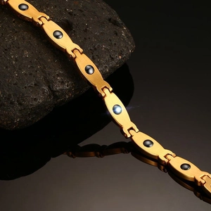 Detailed close-up of golden stainless steel H-link magnetic bracelet with black zircon inlays