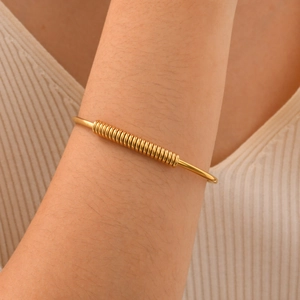 Macro detail of gold spring element coil on minimalist stainless steel cuff bracelet