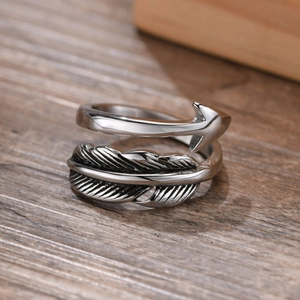 Macro shot of vintage stainless steel feather and arrow ring with antique finish on wood