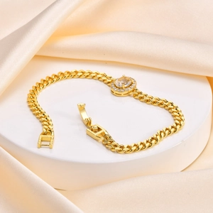 Close-up of a vintage gold Cuban chain bracelet with an oval zircon on a silk background