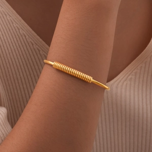 Detail of a gold spring-style bangle on a wrist showing the spiral wire wrap design