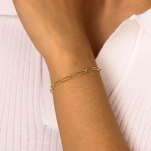 Close-up of a delicate gold faceted square link chain bracelet worn on a woman wrist