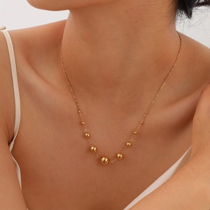 Gros plan d'un collier élégant à perles dorées polies porté par un mannequin