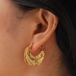 Gold stainless steel C-shaped hoop earring with irregular embossed texture on model