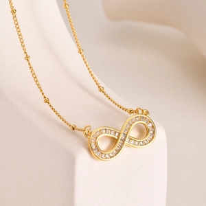 Detailed view of infinity pendant necklace with cubic zirconia on a minimalist stand