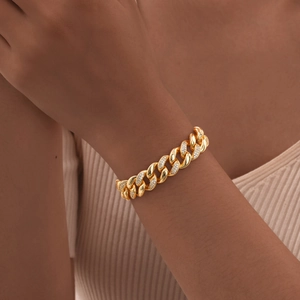 Close-up of a gold Cuban chain bracelet with micro-pave zircon links on a model's wrist