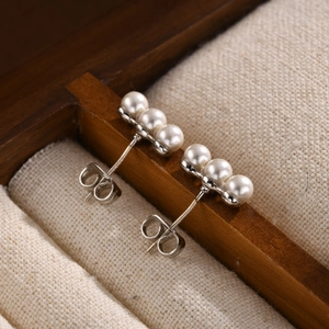Elegant silver earrings with three lined pearls on a premium jewelry box lining