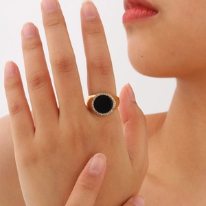 Détail d'une bague chevalière dorée avec onyx noir entouré de zircons blancs brillants