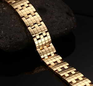 Macro shot of gold stainless steel bracelet with textured links on black volcanic stone